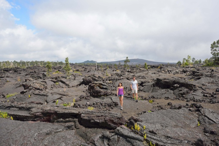 couple hiking in volcanic rocks on kilauea volcano in big island